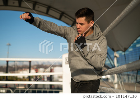 A man in a hoody trains in boxing at the stadium.  101147130