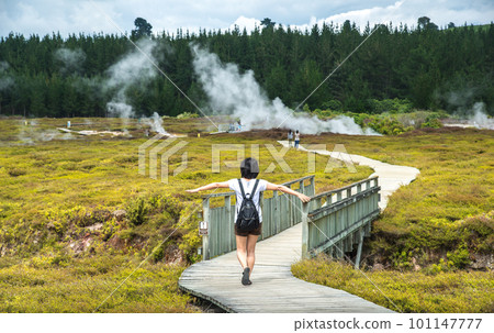 Happiness Asian tourist walking on the boardwalk over geothermal area of Crater of the moon in Taupo, New Zealand. Happiness Asian tourist walking on the boardwalk over geothermal area of Crater of the moon in Taupo, New Zealand. 101147777