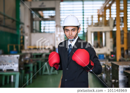 Asian businessman with hardhat and Boxing gloves ready to fight 101148969