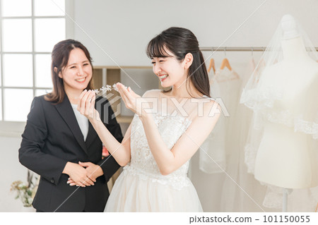 一位穿著婚紗的新娘和一位選擇頭飾和髮飾的婚禮策劃師女士 一位穿著婚紗的新娘和一位選擇頭飾和髮飾的婚禮策劃師女士 101150055