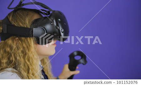 A teenage girl plays a virtual game in black virtual reality glasses. 101152076