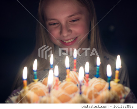 Teen girl admires burning candles at cake on her birthday. Teen girl admires burning candles at cake on her birthday. 101152092