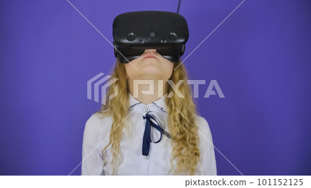 A teenage girl plays a virtual game in black virtual reality glasses. 101152125
