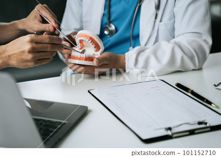 Dentist writing report working with tooth x-ray film model and equipment used in the treatment of dental. 101152710