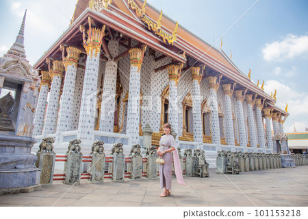 Young woman wearing Thai dress with accessories holding a bag at Wat Arun Ratchawararam It is a popular destination for tourists around the world. Bangkok, Thailand Young woman wearing Thai dress with accessories holding a bag at Wat Arun Ratchawararam It is a popular destination for tourists around the world. Bangkok, Thailand 101153218