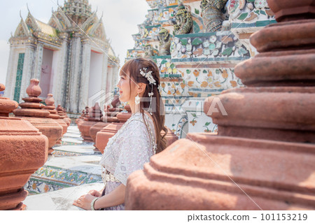 Young woman wearing traditional Thai dress stands at Wat Arun, a popular destination for tourists around the world. Bangkok Thailand Young woman wearing traditional Thai dress stands at Wat Arun, a popular destination for tourists around the world. Bangkok Thailand 101153219