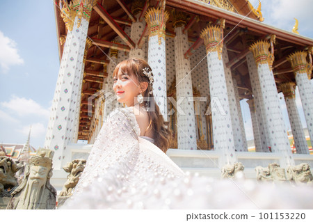 Close up of a young woman wearing traditional Thai dress with accessories standing at Wat Arun, a popular place for tourists around the world. Bangkok Thailand Close up of a young woman wearing traditional Thai dress with accessories standing at Wat Arun, a popular place for tourists around the world. Bangkok Thailand 101153220