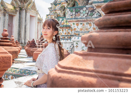 Young woman wearing traditional Thai dress stands at Wat Arun, a popular destination for tourists around the world. Bangkok Thailand Young woman wearing traditional Thai dress stands at Wat Arun, a popular destination for tourists around the world. Bangkok Thailand 101153223