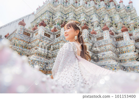 Close up of a young woman wearing traditional Thai dress with accessories standing at Wat Arun, a popular place for tourists around the world. Bangkok Thailand Close up of a young woman wearing traditional Thai dress with accessories standing at Wat Arun, a popular place for tourists around the world. Bangkok Thailand 101153400
