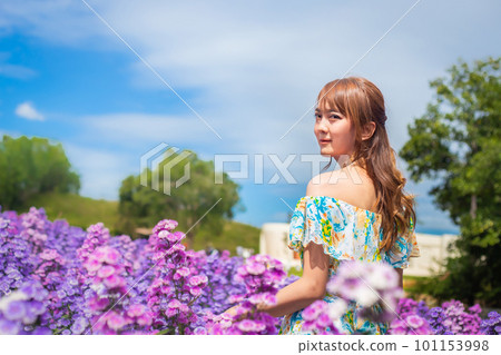 woman wearing a long dress in a field of margaret flowers exudes a relaxed and freedom. Soft and select focus 101153998