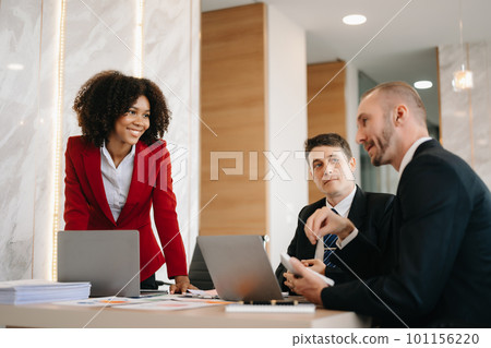 Happy businesspeople while collaborating on a new project in an office. Group of diverse businesspeople using a laptop and tablet in office.. 101156220