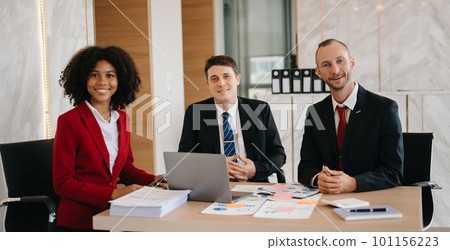 Happy businesspeople while collaborating on a new project in an office. Group of diverse businesspeople using a laptop and tablet in office.. Happy businesspeople while collaborating on a new project in an office. Group of diverse businesspeople using a laptop and tablet in office.. 101156223
