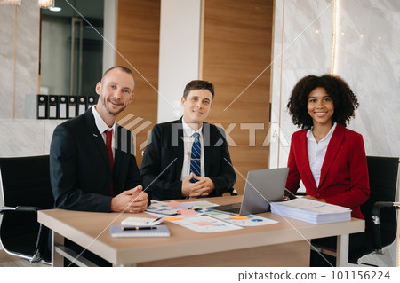 Happy businesspeople while collaborating on a new project in an office. Group of diverse businesspeople using a laptop and tablet in office.. 101156224