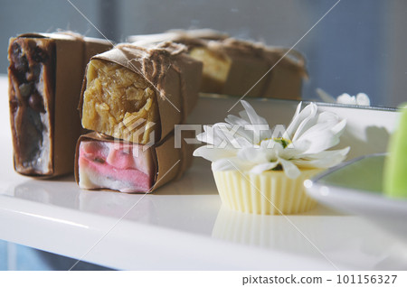 Still life with cold pressed handmade soap bars wrapped in craft paper on white ceramic surface, against bathroom mirror background. Wellness. Skin and body care. Home spa and body relax concept 101156327