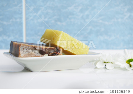 Close-up of organic craft soap bars with natural herbs ingredients and essential oils, on the soap holder against a blue marble bathroom wall background. Ecologically friendly cosmetic beauty products Close-up of organic craft soap bars with natural herbs ingredients and essential oils, on the soap holder against a blue marble bathroom wall background. Ecologically friendly cosmetic beauty products 101156349