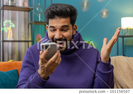 Happy indian man at home use smartphone typing browsing wow yes found out great big win celebrate Happy indian man at home use smartphone typing browsing wow yes found out great big win celebrate 101156507