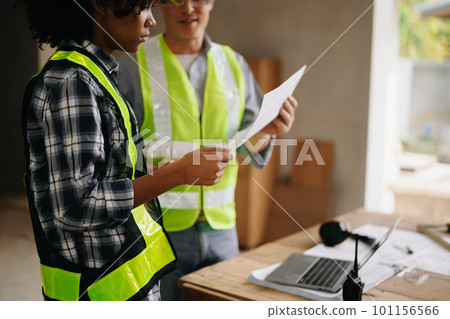 Contractor and architect looking at plan, tablet, laptop and talking about working on big project. Building in construction process interior. team work . 101156566
