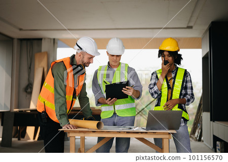 Contractor and architect looking at plan, tablet, laptop and talking about working on big project. Building in construction process interior. team work . Contractor and architect looking at plan, tablet, laptop and talking about working on big project. Building in construction process interior. team work . 101156570