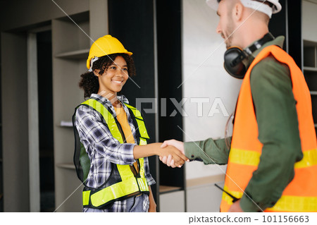 Construction team shake hands greeting start new project plan behind yellow helmet on desk in office center to consults about their building project.. 101156663