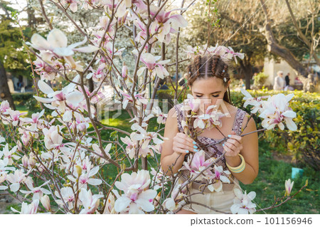 Magnolia flowers, a girl smells a blooming magnolia in the park in the sun, enjoys her vacation. Magnolia flowers, a girl smells a blooming magnolia in the park in the sun, enjoys her vacation. 101156946