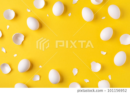 Minimalistic Easter background. White Easter eggs and shells on a bright yellow background. Card with a place for text. Top view. 101156952