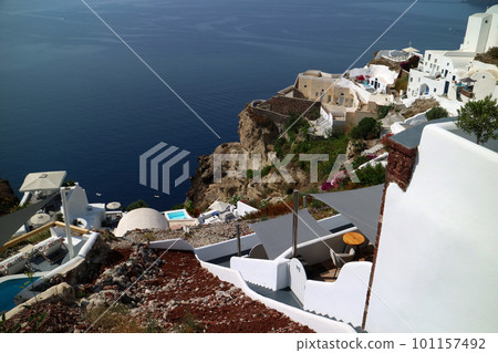 A row of white houses built on the volcanic rocks of a precipitous cliff 101157492
