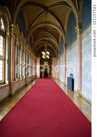 BUDAPEST, HUNGARY - 03 MAR 2019: Long hallway with red carpet on marble floor and chandelier on the ceiling in the Hungarian Parliament building 101157585