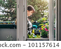 Smiling woman gardening on balcony on sunny day 101157614