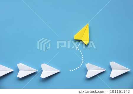 Yellow paper airplane origami leaving other white airplanes on blue background with customizable space for text or ideas. Leadership skills concept and copy space. 101161142