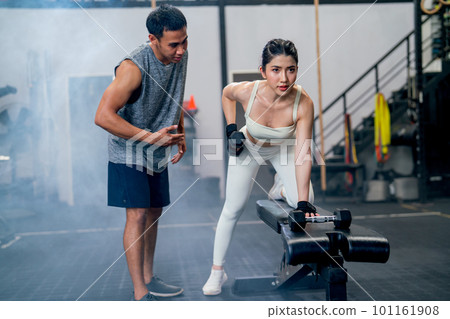 Wide shot of Asian sport woman sit and stay in position of exercise with hold dumbbells look forward Wide shot of Asian sport woman sit and stay in position of exercise with hold dumbbells look forward 101161908