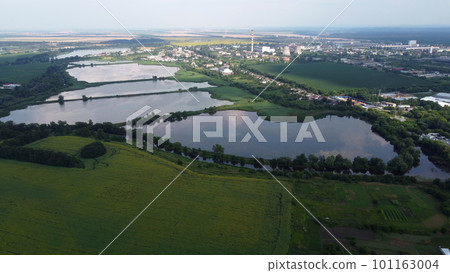 Beautiful panoramic urban landscape on summer day. Industrial lakes for fish farming, agricultural farm fields, city Industrial Zone building, thermal power plant. Aerial drone view. Top view Beautiful panoramic urban landscape on summer day. Industrial lakes for fish farming, agricultural farm fields, city Industrial Zone building, thermal power plant. Aerial drone view. Top view 101163004