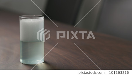 pour green soda drink from a bottle into highball glass on walnut table with copy space 101163216