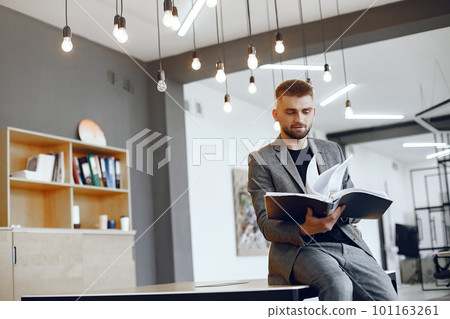 Businessman working in the office.Man holds a folder. Guy is sitting in the office Businessman working in the office.Man holds a folder. Guy is sitting in the office 101163261