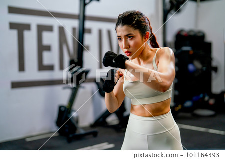 Asian woman action of boxing and training alone in fitness gym and she look concentrate to practice Asian woman action of boxing and training alone in fitness gym and she look concentrate to practice 101164393