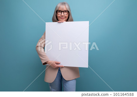 close-up of a confident mature woman in a jacket with a mocap abstract poster on a bright background close-up of a confident mature woman in a jacket with a mocap abstract poster on a bright background 101164588