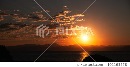 Picturesque view Sunrise From Corfu Island Overlooking Mountains Of Balkan Peninsula Of Greece, Moraitika, Corfu. In Foreground Are Silhouettes Of Trees And Water Slide. 101165258
