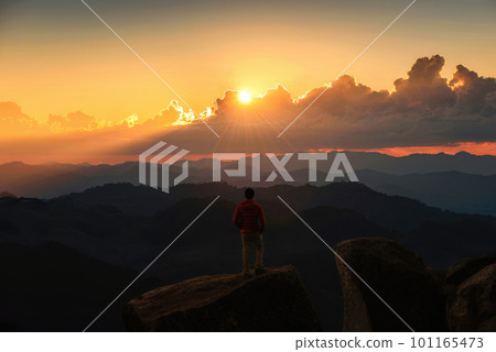 Hiker man standing and looking the view on top of mountain during sunset in tropical rainforest at national park 101165473