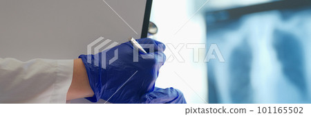 Doctor examines x-ray of lungs and holds clipboard Doctor examines x-ray of lungs and holds clipboard 101165502