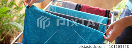 Woman hangs blue towel on dryer closeup Woman hangs blue towel on dryer closeup 101165558