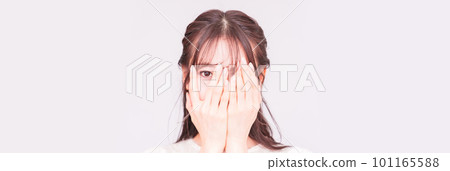 A young woman peeping through her fingers [ Image of suspicious gaze ] 101165588