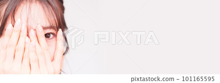 A young woman peeping through her fingers [ Image of suspicious gaze ] 101165595