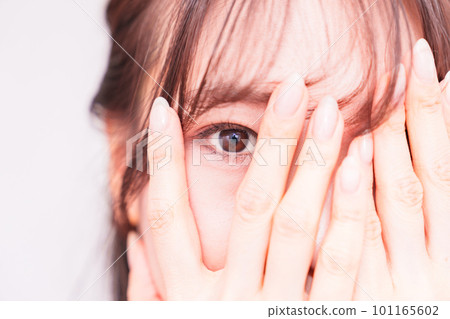 A young woman peeping through her fingers [ Image of suspicious gaze ] 101165602