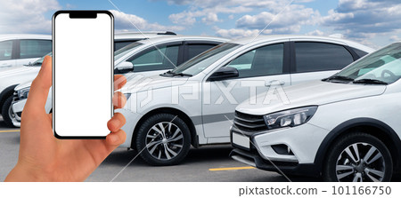 Hand with phone on a background of rows of cars. Car sales. 101166750