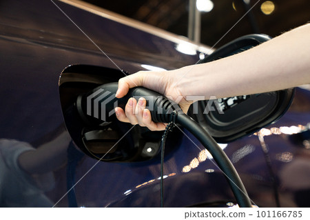 Woman holding plug of electric car charging station Woman holding plug of electric car charging station 101166785