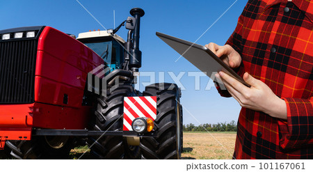 Farmer with digital tablet controls an autonomous tractor on a smart farm 101167061