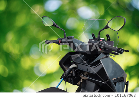 Electric scooter with connected charging cable on a green background Electric scooter with connected charging cable on a green background 101167068