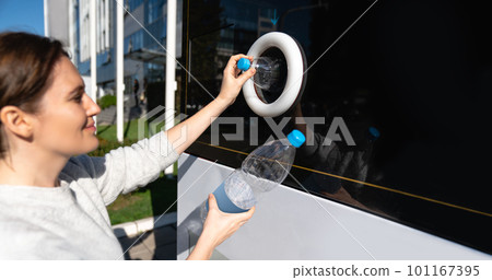 Woman uses a self service machine to receive used plastic bottles and cans on a city street 101167395