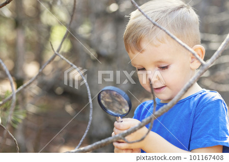 Curious boy is exploring nature with magnifying glass outdoors 101167408