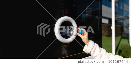 Woman uses a self service machine to receive used plastic bottles and cans on a city street 101167444