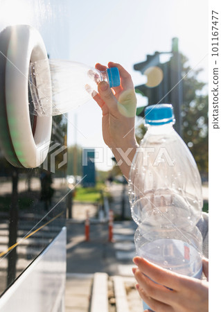 Woman uses a self service machine to receive used plastic bottles and cans on a city street 101167477
